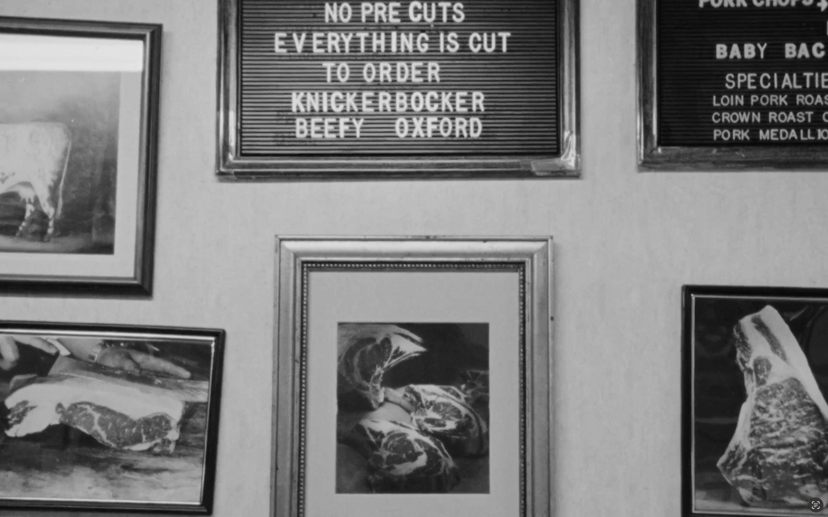 Vintage-style meat display with framed images and a sign on a wall.