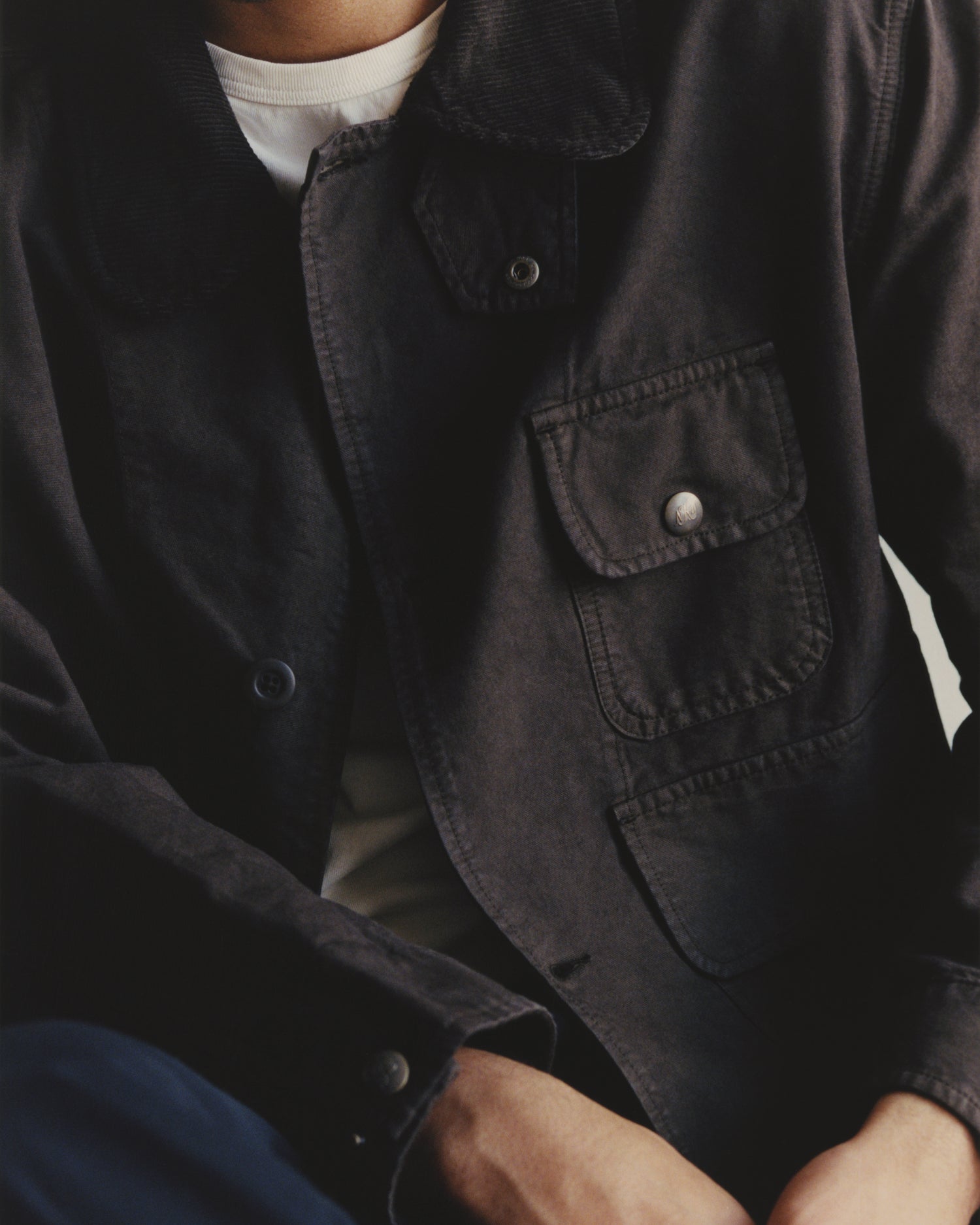 Close-up of a person wearing a dark jacket with a buttoned pocket.