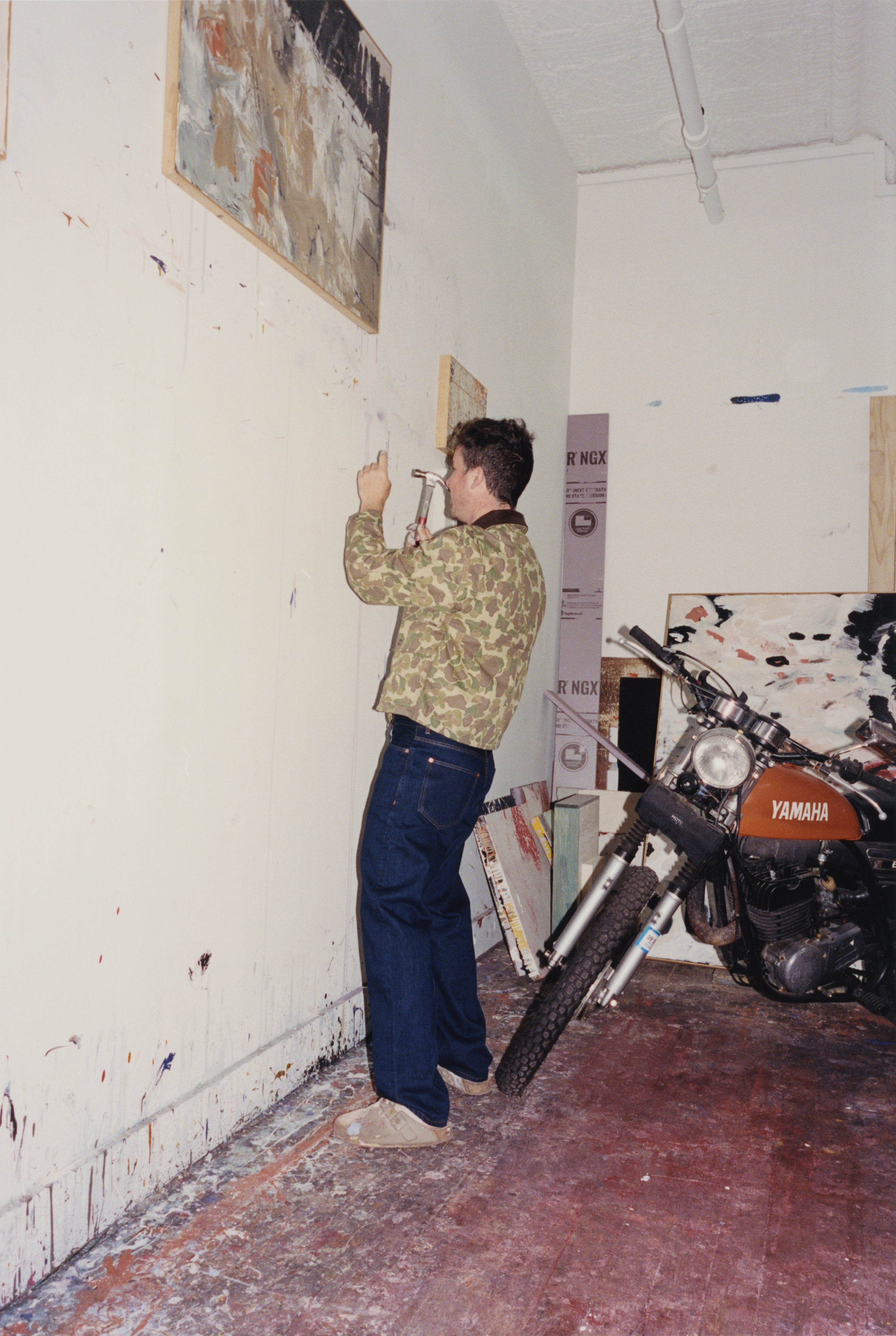 Joe Henry Baker hammering a nail into the wall in his studio