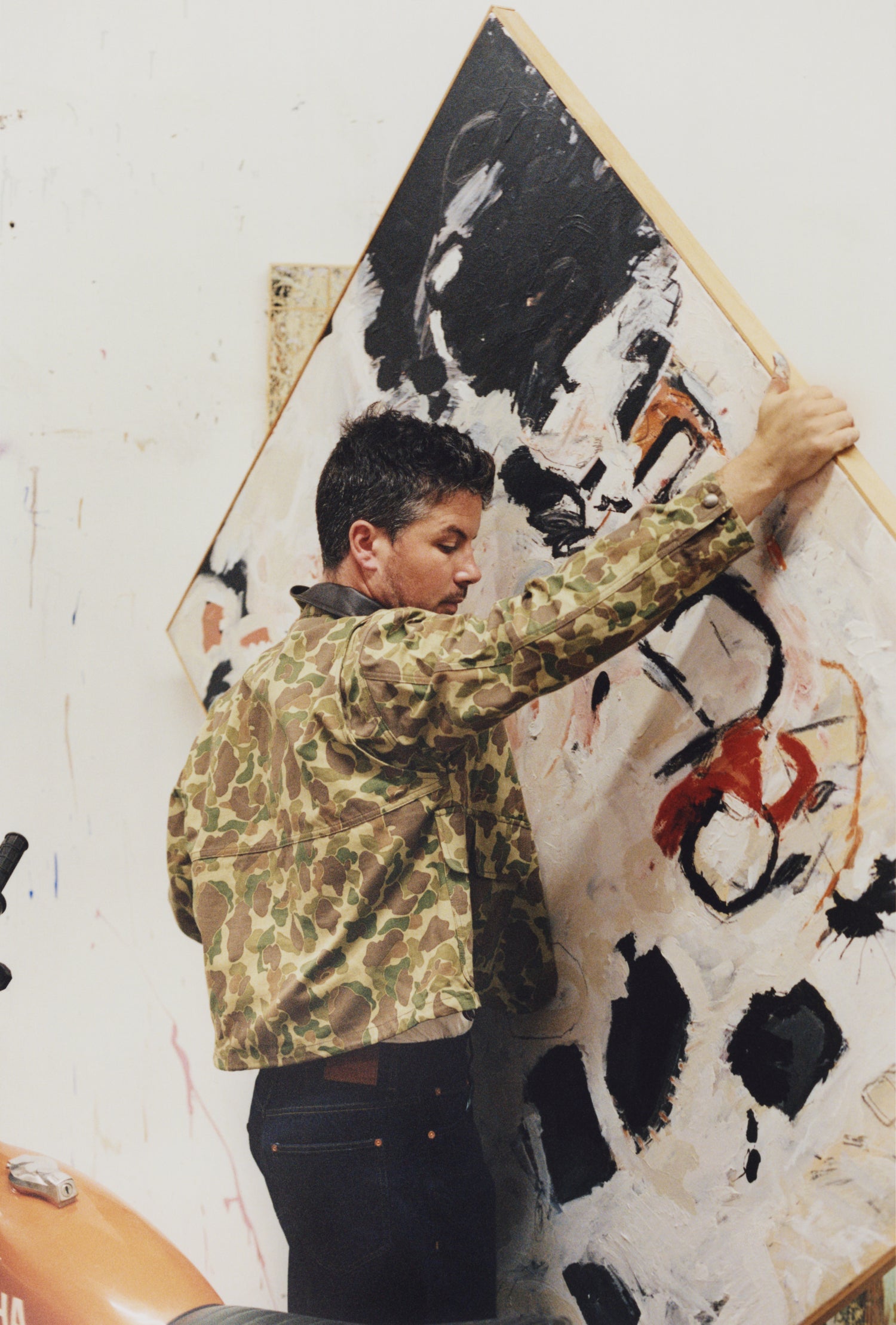 Joe Henry Baker carrying his painting in his studio
