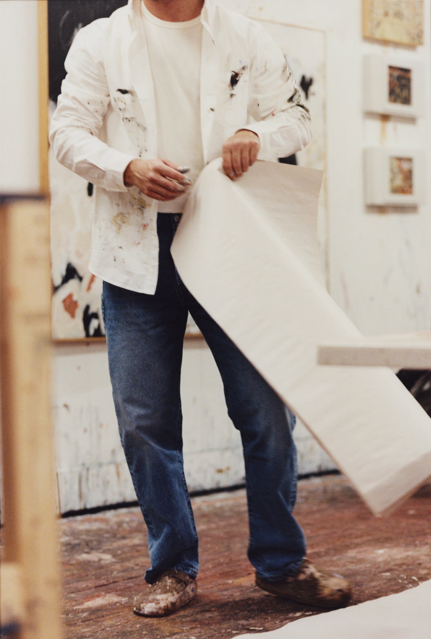 Artist Joe Henry Baker wearing a paint smeared white oxford shirt in his studio