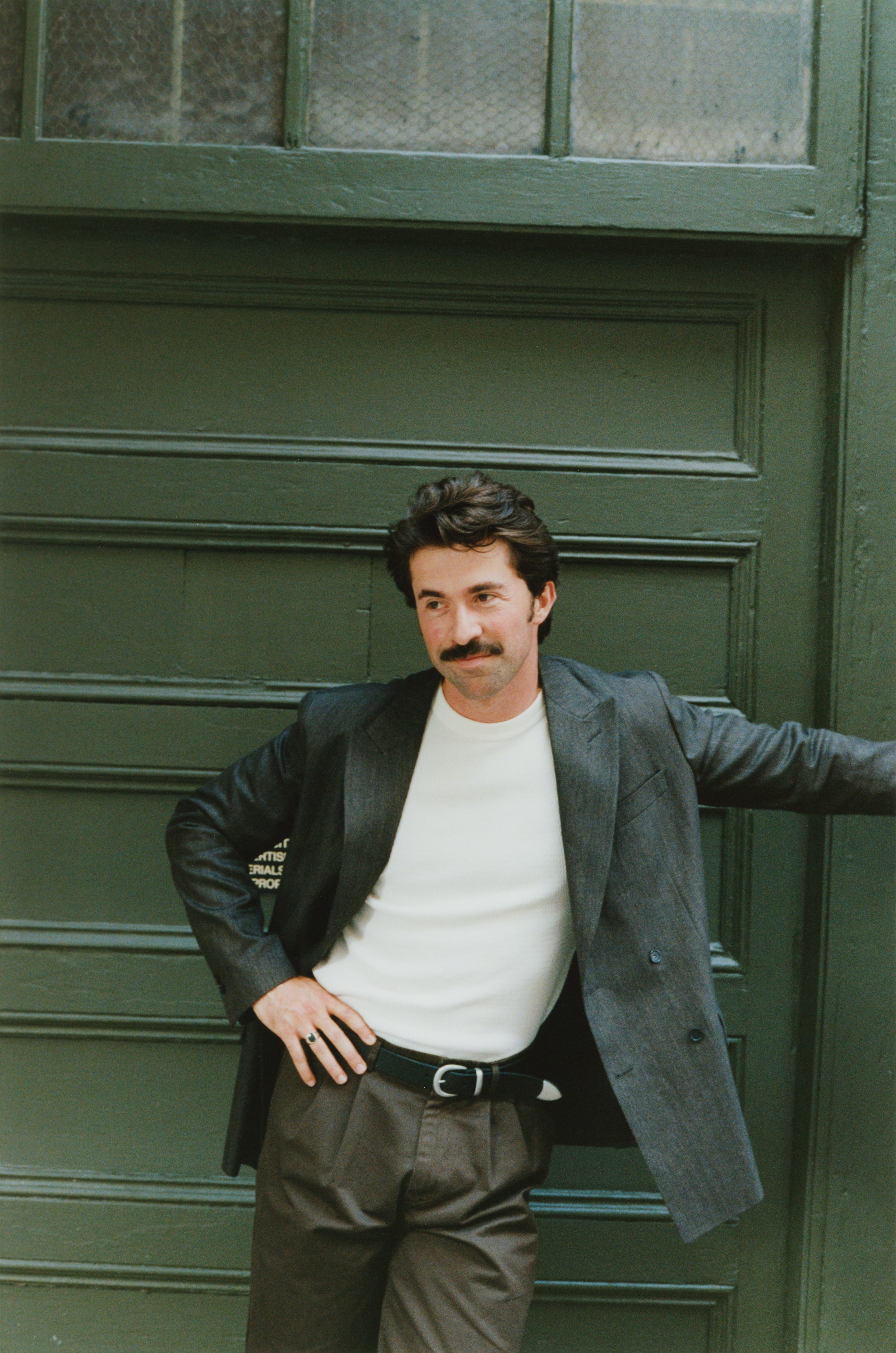 Albert Muzquiz wearing a thermal and suit jacket in front of a green city door