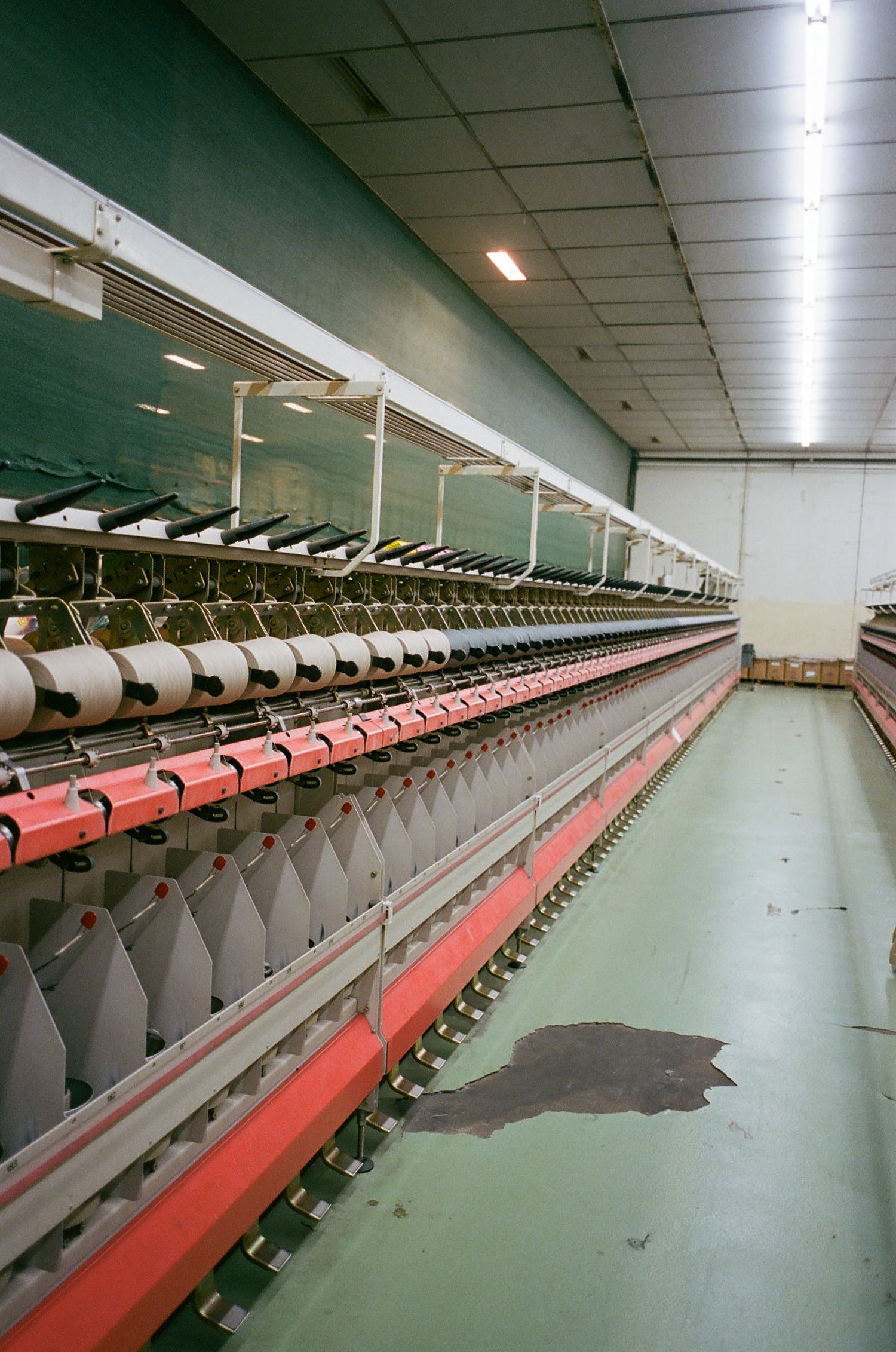 Textile factory with rows of spools on a green floor.