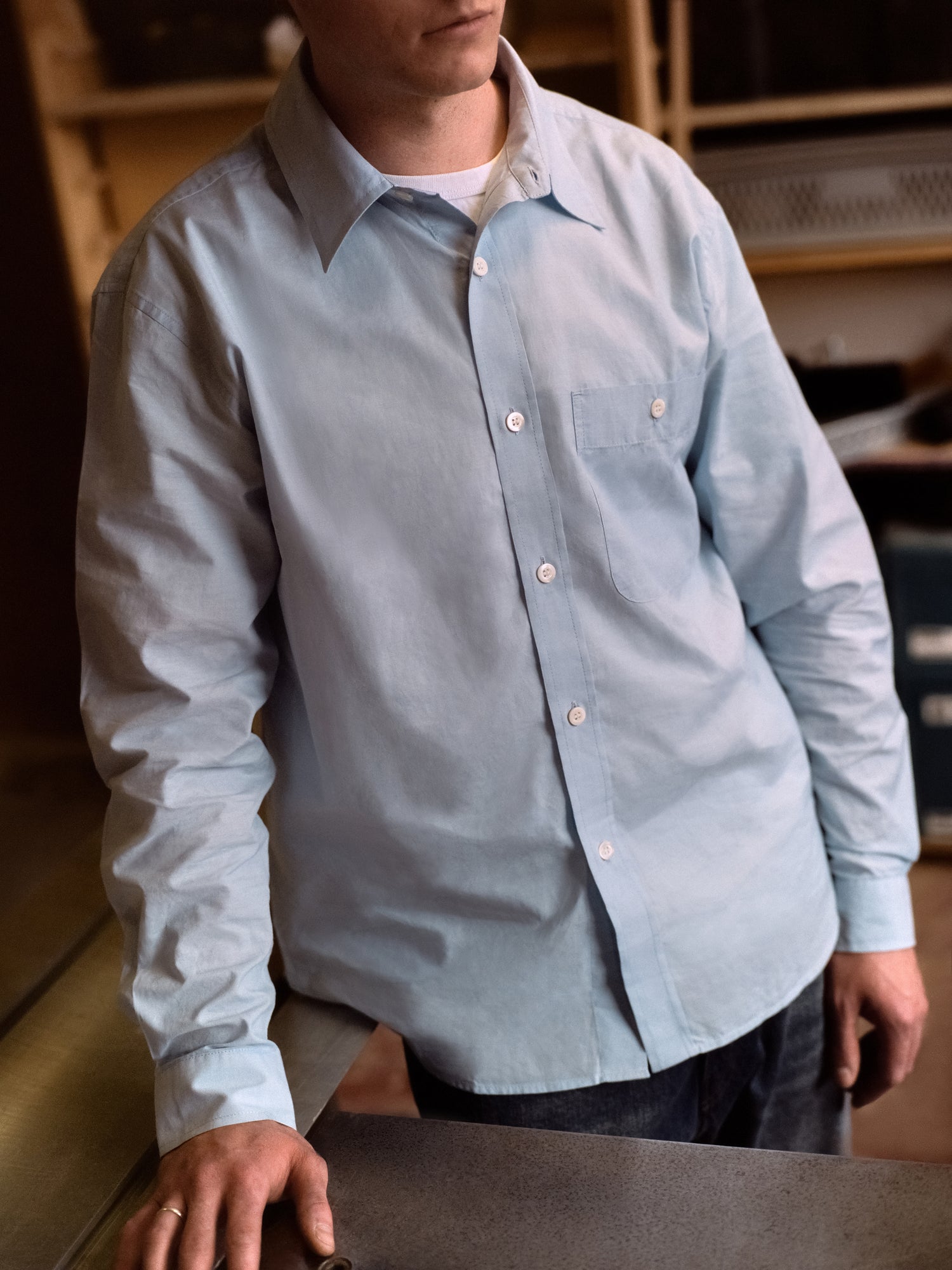 Person wearing a light blue button-up shirt in an indoor setting