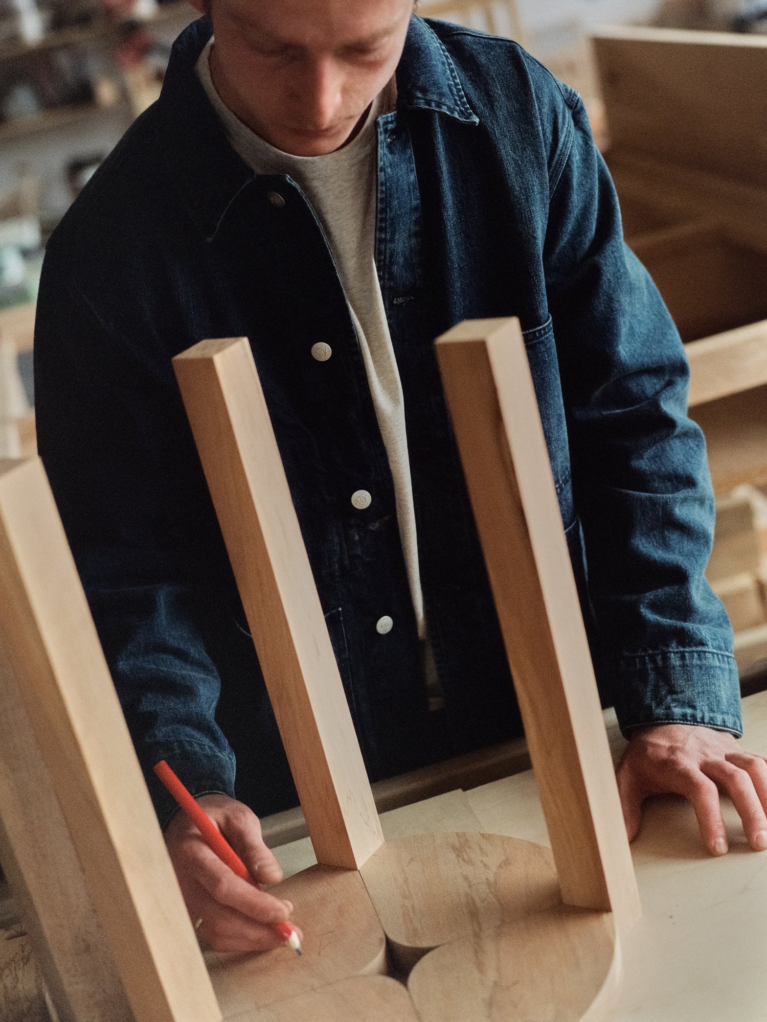Person assembling wooden furniture with a pen in a workshop setting